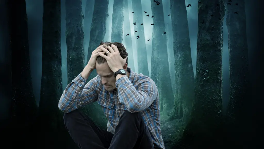 Man worried and depressed in dark woods with crows behind him. 