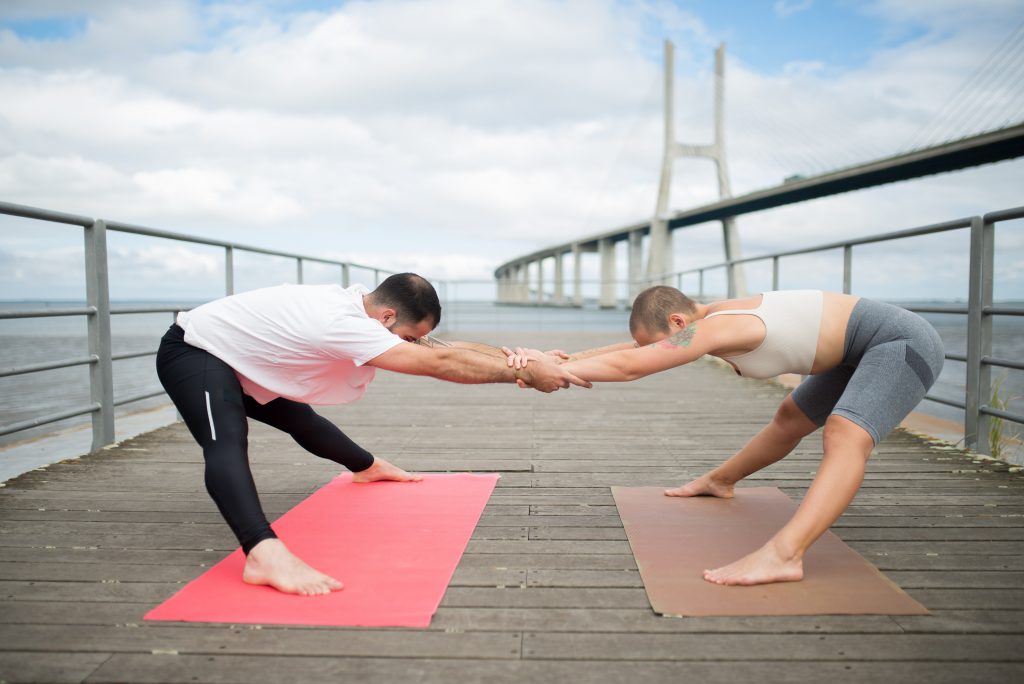 Couple doing yoga on a bridge
